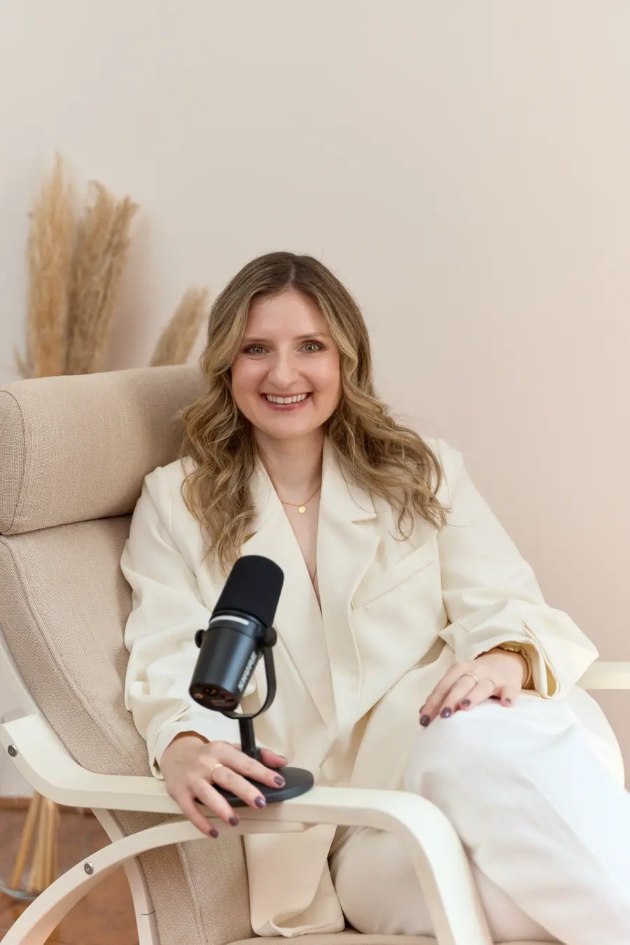 Woman seated with a podcast microphone, smiling