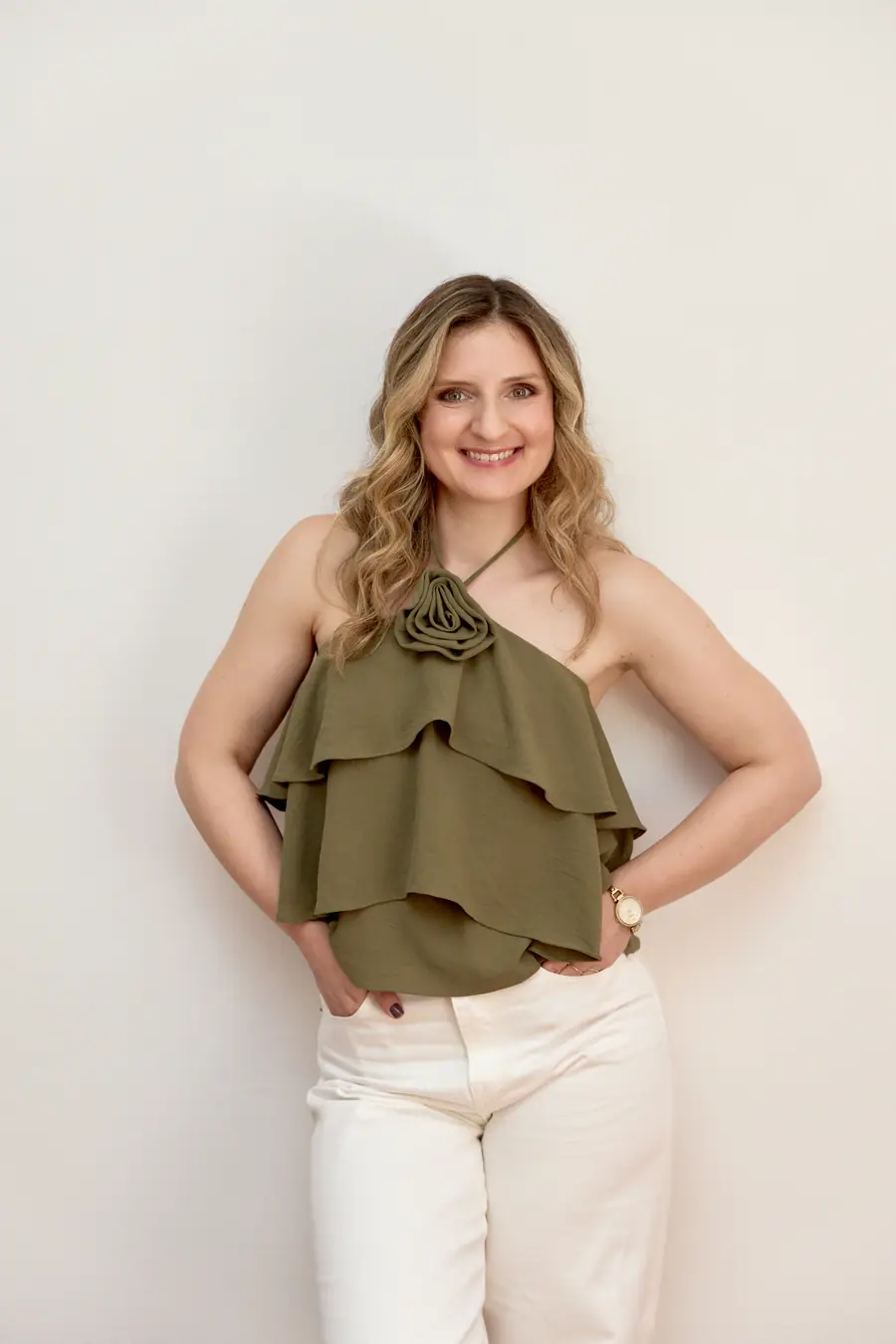 Woman in an olive top standing against a plain wall
