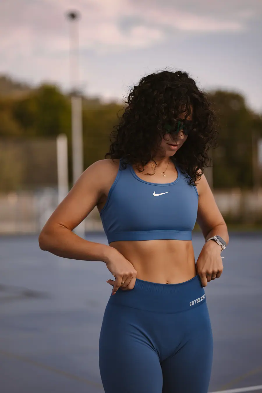 Woman on a sports court looking down, evening light