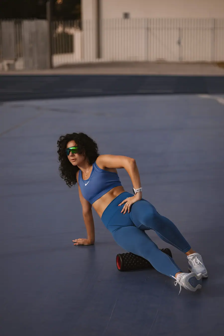 Woman low to the ground mid exercise on a blue court