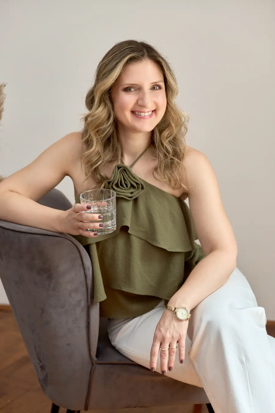 Woman in an olive top seated in an armchair with a glass of water